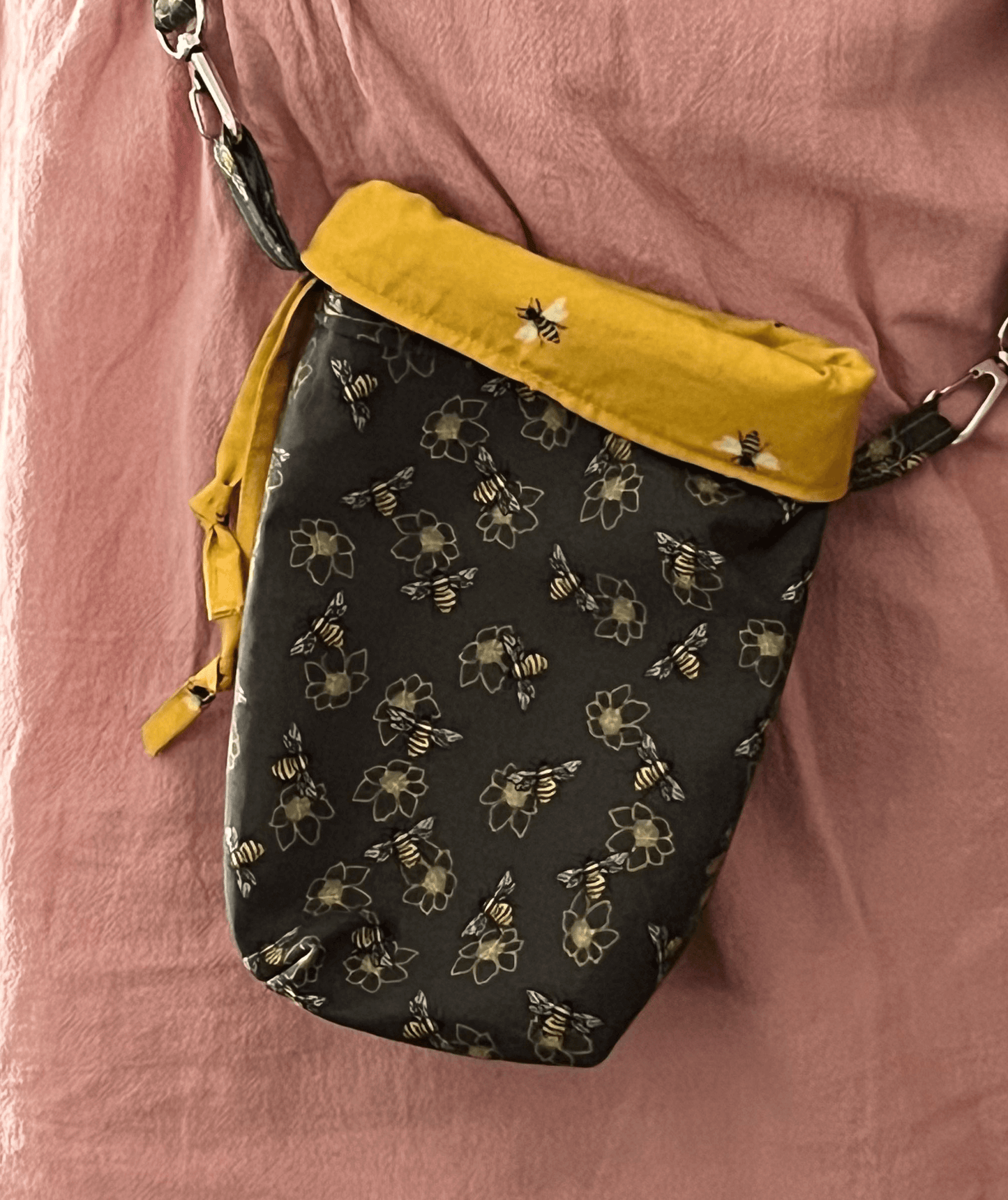 Small bag with bee pattern and yellow interior on a pink background