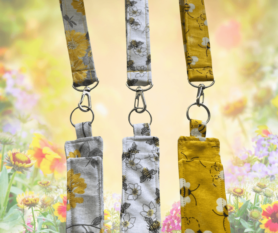 Three floral lanyards with matching keychains against a blurred floral background