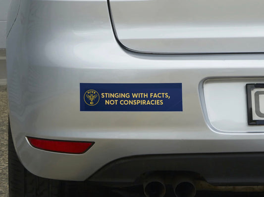 Bumper sticker on a car reading 'Sticking with facts, not conspiracies' on a silver vehicle.
