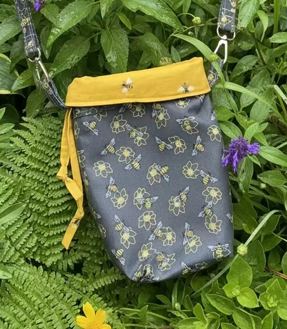 Handbag with bee and flower pattern on a green leaf background