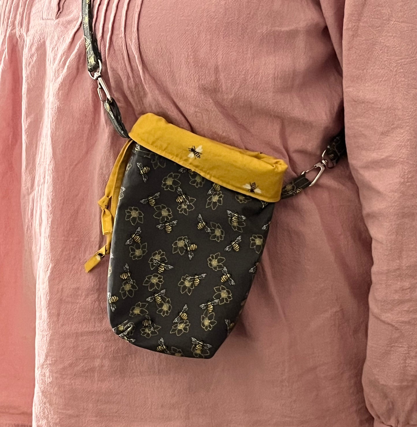 Black bee patterned bag with yellow trim worn over a pink jacket