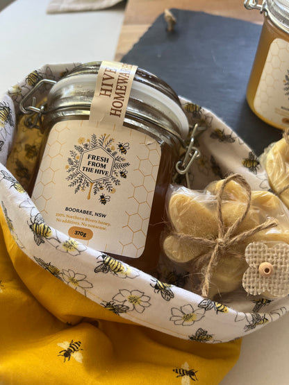 Jar of honey with a decorative label on a fabric background with bee patterns