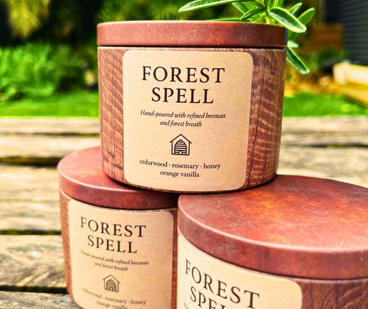 Three 'Forest Spell' candles stacked on a wooden surface with a natural background.