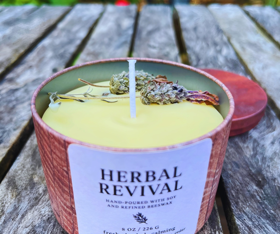 Candle labeled 'Herbal Revival' on a wooden surface