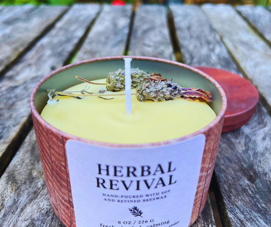 Candle labeled 'Herbal Revival' on a wooden surface