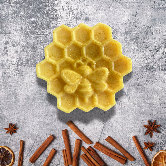 Yellow honeycomb-shaped soap on a gray surface with cinnamon sticks and star anise.