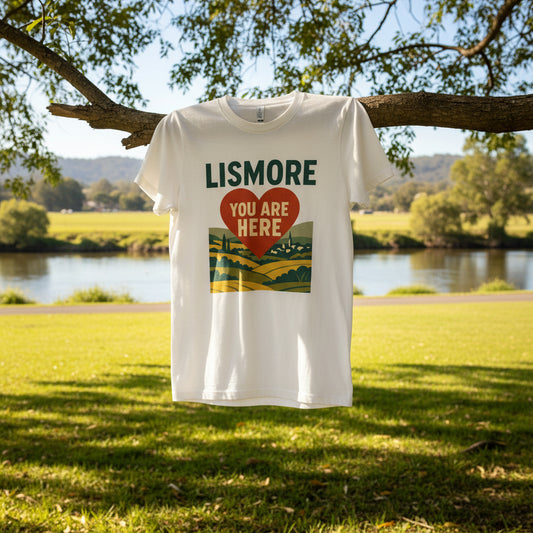 White t-shirt with 'Lismore You Are Here' design featuring a heart and landscape on a white background