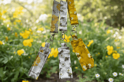 Three fabric keychains with floral patterns on a yellow and green leafy background