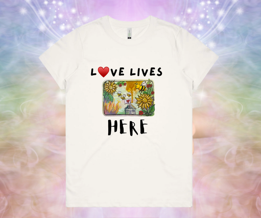 White t-shirt with 'Love Lives Here' text and colorful design on a multicolored background